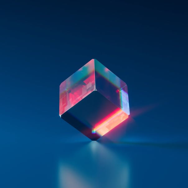 glass cube standing on corner refracting multiple colors with reflection on ground